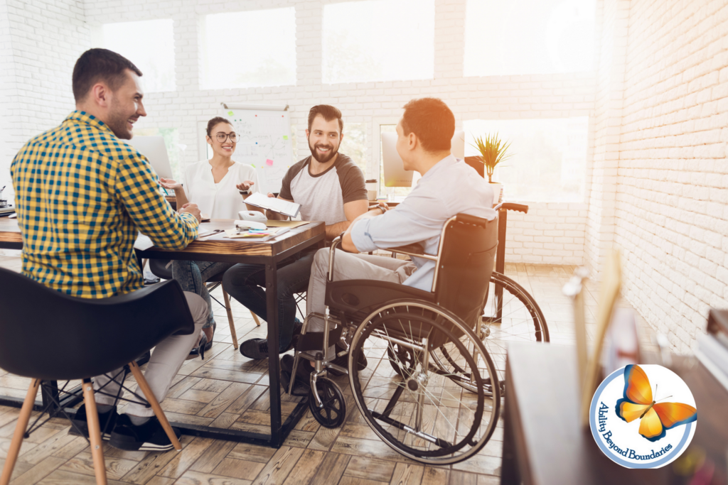 A smiling man sitting in a Wheelchair welcomes his colleagues in a meeting